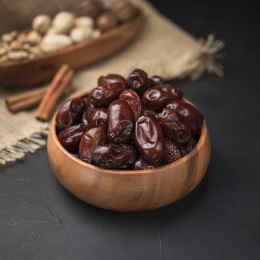 Kare bir ahşap kasede kurumuş meyve, koyu bir arka plan ve çuval bezi.