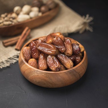 Kare bir ahşap kasede kurumuş meyve, koyu bir arka plan ve çuval bezi.