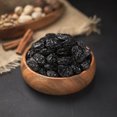 Kare bir ahşap kasede kurumuş meyve, koyu bir arka plan ve çuval bezi.