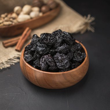 Kare bir ahşap kasede kurumuş meyve, koyu bir arka plan ve çuval bezi.