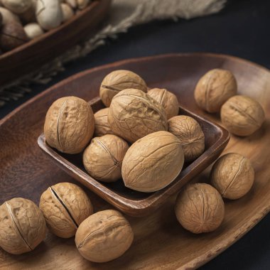 Kare bir ahşap kasede fındık ve arka planda oval ahşap tepsi ve çuval bezi.