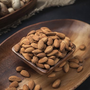 Kare bir ahşap kasede fındık ve arka planda oval ahşap tepsi ve çuval bezi.