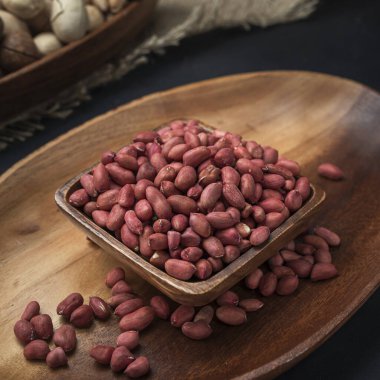 Kare bir ahşap kasede fındık ve arka planda oval ahşap tepsi ve çuval bezi.