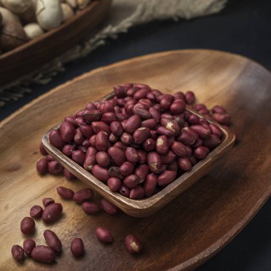 Kare bir ahşap kasede fındık ve arka planda oval ahşap tepsi ve çuval bezi.