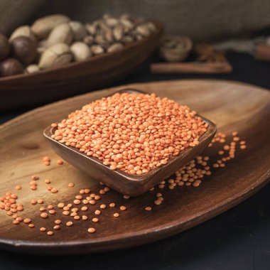 Kare bir ahşap kasede tahıl ve tahıllar ve koyu bir arka planda oval tahta tepsi ve çuval bezi.