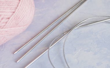 Açık mavi arka planda iplik örgü iğneleri