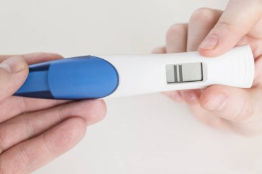 Pozitif elektronik gebelik testi beyaz bir arkaplanı kapatıyor