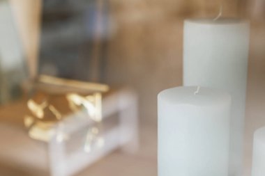 Dolapta beyaz dekoratif mumlar, cam kapılı ve yansımalı.