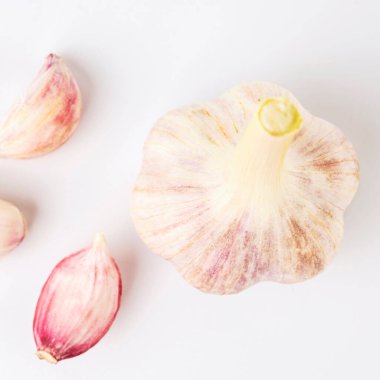 Beyaz arka planda karanfilli taze sarımsak var.