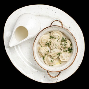 Beyaz tabakta ekşi kremalı domuz köftesi. Üst fotoğraf, izole edilmiş, siyah arkaplan.