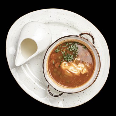 Solyanka çorbası, beyaz tepside kremalı, siyah arkaplan, izole edilmiş.