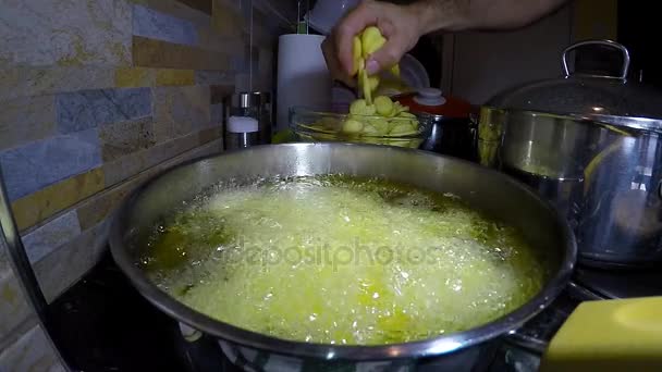 Картофель в кастрюлю с горячим маслом — стоковое видео