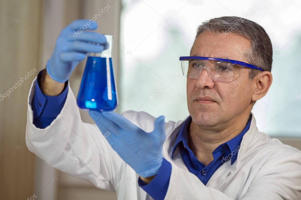  Middle Aged Scientist Examining a Beaker of Blue Fluid