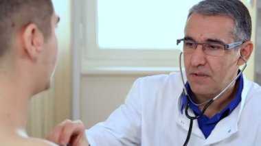 Doktor dinlemek için kalp atışı genç adam spor tıp doktor genç atlet stetoskop ile kontrol. Doktor ve hasta tıbbi test sırasında.