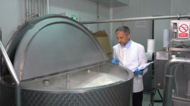 Süt bitkisi teknolojisi, pano ile süt pastörize işlemini kontrol ediyor. Süt İşleme Tesisinde Süt Pastörizasyonu. Pastörizasyon tankının içindeki süt. Mandıra Gıda Güvenliği.