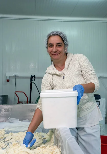 Χαμογελώντας γυναίκα εργαζόμενος στη γραμμή παραγωγής τυριών σε ένα εργοστάσιο γαλακτοκομικών προϊόντων — Φωτογραφία Αρχείου