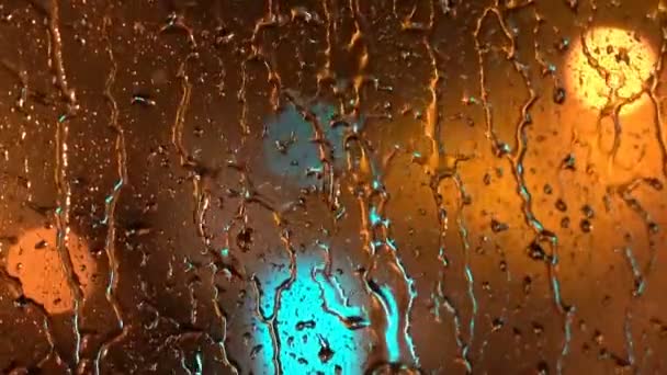 Pluie mélancolique - Ville à travers la fenêtre pluvieuse la nuit. Vue de l'éclairage nocturne trouble de la ville à travers la fenêtre avec des gouttes de pluie . 