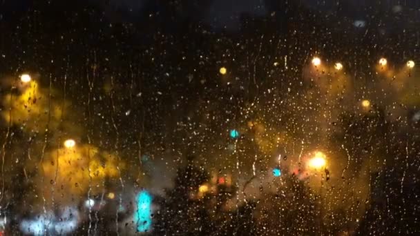 雨の夜の街の光と交通 雨が降る窓から見る都市の夜のイルミネーション — ストック動画