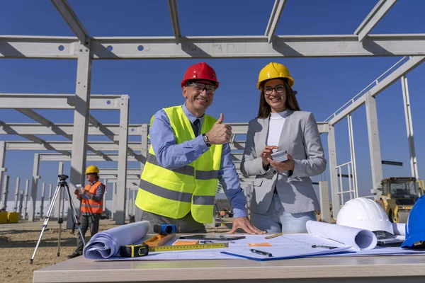 Heureux architecte et homme d'affaires féminin avec pouce levé regardant la caméra sur le chantier de construction — Photo