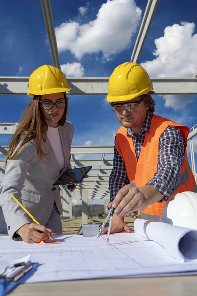 Kvinnlig arkitekt och ingenjör kontrollerar byggplanen på byggarbetsplatsen — Stockfoto