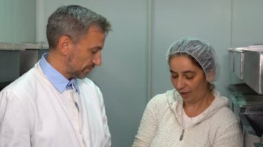 Gıda Fabrikası 'nda İki Çalışan Video Montaj Yapıyor. Süt bitkisi işçisi kremalı (pıhtılaşmış krema) ayrıştırma üretim hattı. Süt Ürünleri Üretim Tesisi. 