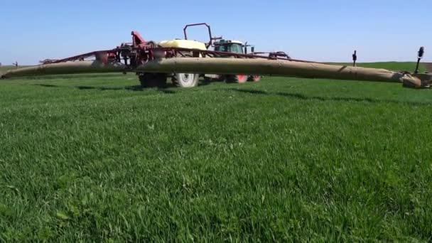 春に麦畑をスプレーするスプレー スローモーション フィールドで働く大規模なマウントされた作物保護スプレーヤー 殺菌剤で若い小麦を噴霧する — ストック動画