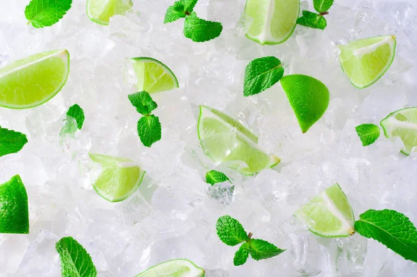 Rodajas frescas de limas verdes y menta sobre cubitos de hielo picados —  Fotos de Stock