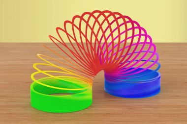 Gökkuşağı renkli plastik, sinsi oyuncak ahşap masa üzerinde. 3D parçalamak