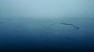 Karamsar bir alacakaranlıkta puslu ve donmuş deniz manzarası