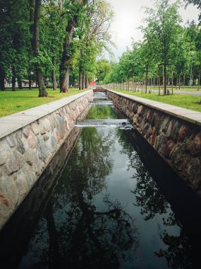 Parkta taş çerçeveli kıyıları olan dar bir kanal