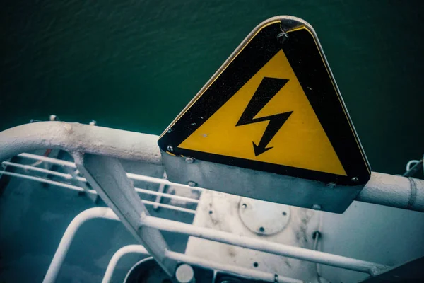 Risk of electric shock sign on a ship\'s reeling