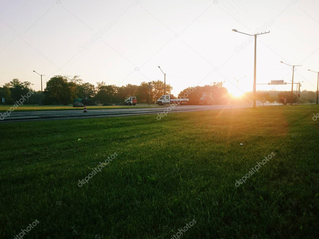 Distant view of cars on a countryside road with sunset in background