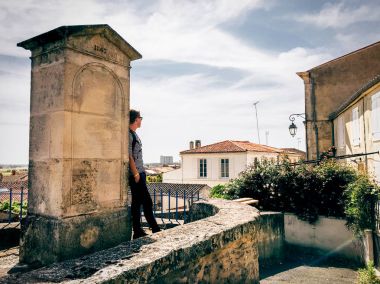 Duvar tarafından ayakta ve uzağa bakarak güneş gözlüklü adam