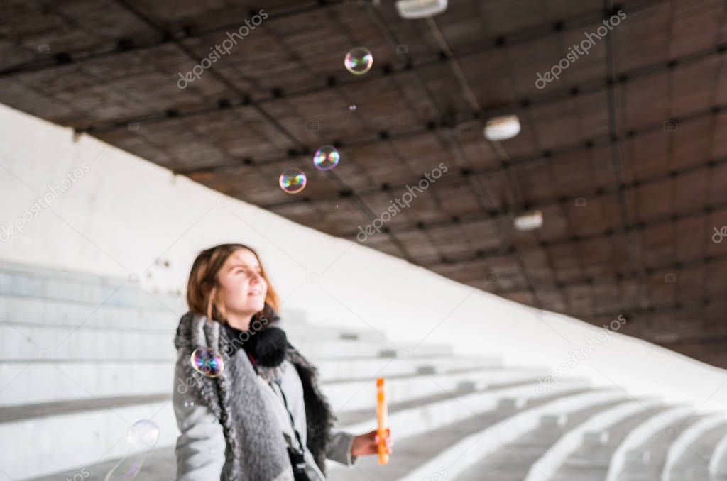 Blurry view of a girl blowing soap bubbles on a neutral background
