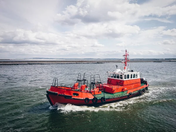 Red tugboat sailing by sea