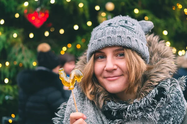 Chica Bonita Sosteniendo Gallo Caramelo Con Brillante Árbol Navidad Fondo —  Fotos de Stock