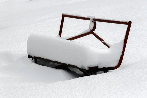 Покрытый большим слоем снежной скамейки в городском парке — стоковое фото