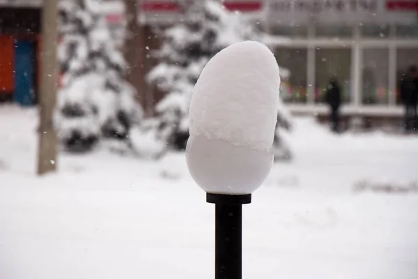 Уличная лампа со снежной шапкой на снежной улице. . — стоковое фото