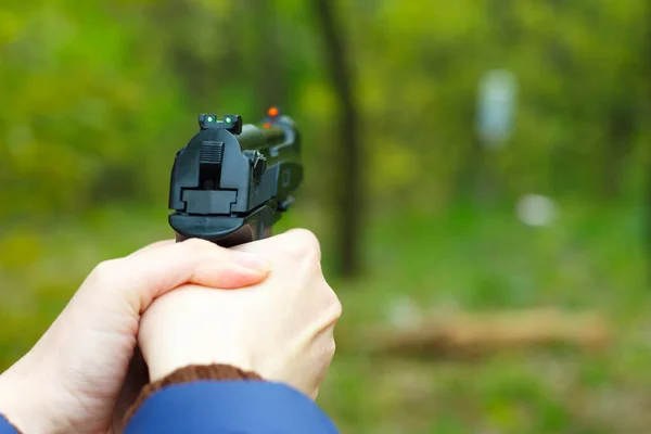 Flickan håller en pistol i sina händer och siktar. — Stockfoto