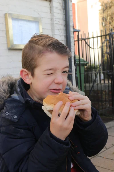 牛肉のハンバーガーを食べる若い美少年 — ストック写真