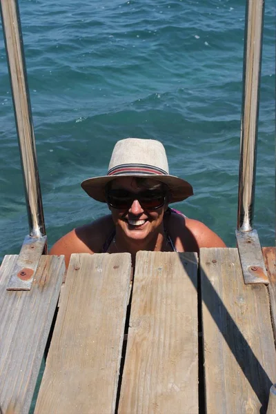 Повзрослевшая английская дама выбирается из моря по лестнице — стоковое фото