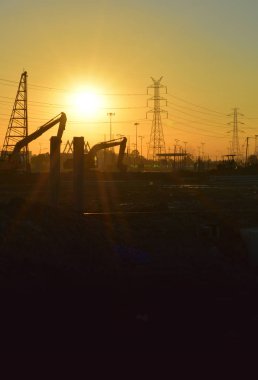 şantiye ve gündoğumu gökyüzü ile elektrik direği.