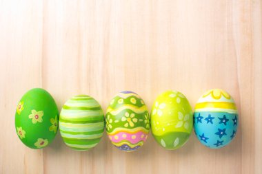 Boya fırçasında renkli yumurtalarla mutlu Paskalyalar. Kahverengi tahta zemin üzerinde fotokopi alanı ile kendiniz yapın..