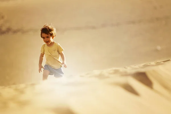 Niño con la camiseta amarilla y pantalones cortos azules en un desierto —  Fotos de Stock