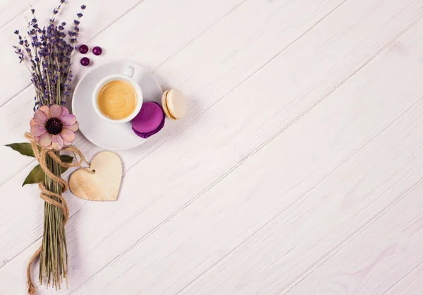 Tasse de café avec deux macarons, bouquet de lavande et coeur en bois. Concept violet et violet sur fond blanc — Photo