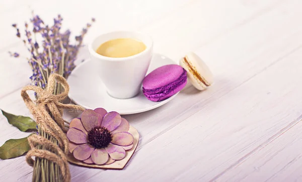 Tasse de café avec deux macarons, bouquet de lavande et coeur en bois. Concept violet et violet sur fond blanc — Photo