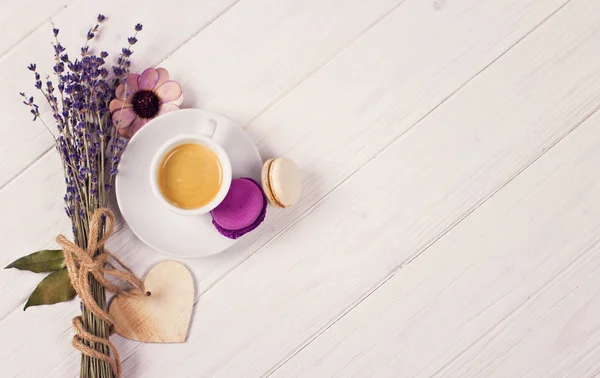 Tasse de café avec deux macarons, bouquet de lavande et coeur en bois. Concept violet et violet sur fond blanc — Photo