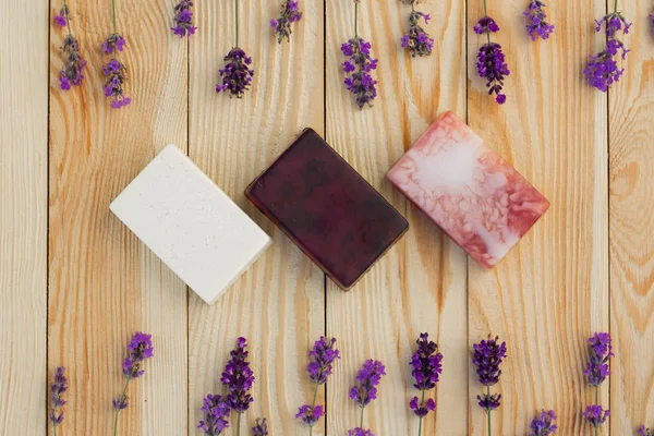 Three different handmade lavender soaps on wooden table framed w