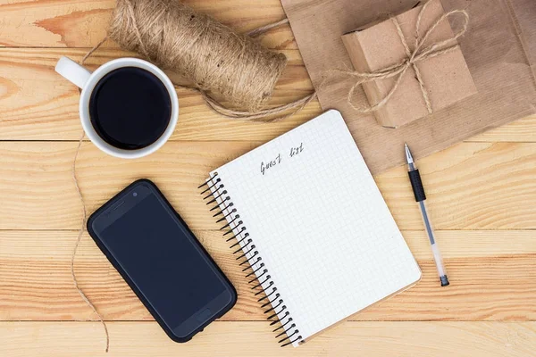 A notebook with an inscription Guest list laying on wooden table