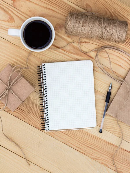 A blank notebook laying on wooden table. It is surrounded by  bl